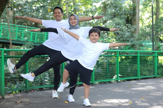 Asian young mother and father practicing yoga and balancing body together with son at the green park. Family fun sport. photo