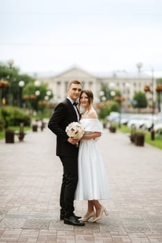 young couple bride and groom in a white short dress photo