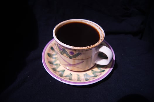 a glass containing brewed black coffee on a black background photo