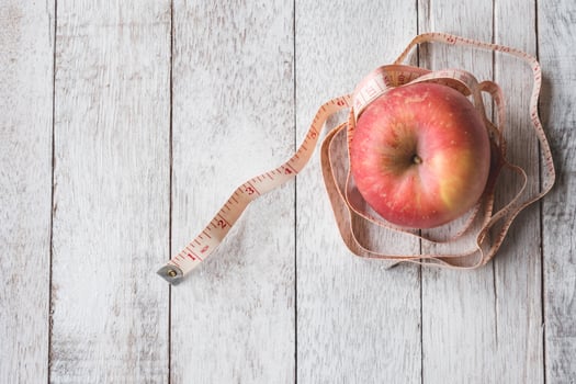 Top view of Red apple with measure tape on white wooden table background photo