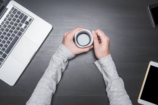 Top view of Male hands holding a coffee cup with laptop, tablet and smart phone on black wooden table background. photo