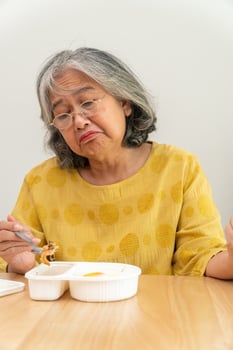 Unhappy Asian senior woman anorexia and say no to ready meals, Elderly home alone and bored food and no appetite photo