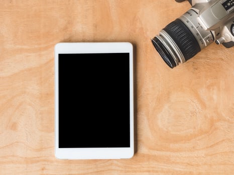 Top view of tablet with camera on wooden table. photo