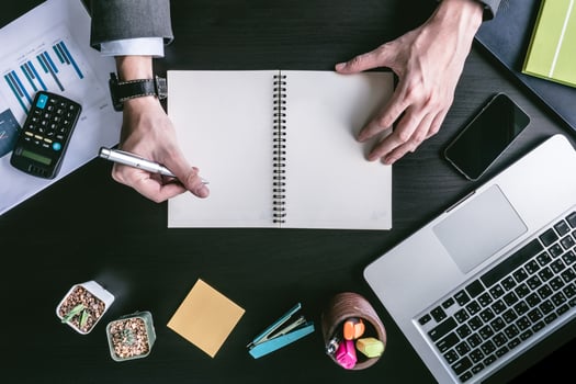 Top view of Businessman writing some data in notebook on the office desk. photo