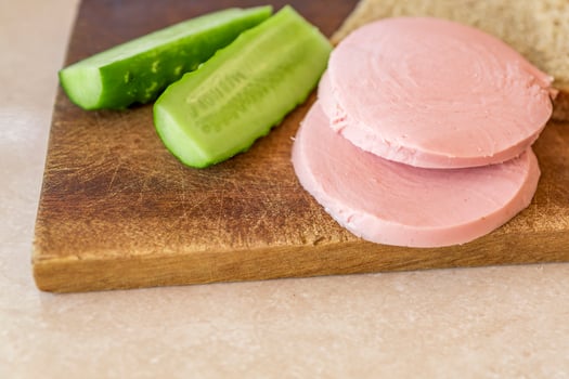 rye bread, cucumber and sausage on brown wooden desk photo