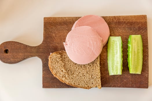 rye bread, cucumber and sausage on brown wooden desk photo