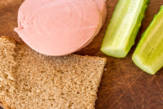 rye bread, cucumber and sausage on brown wooden desk photo