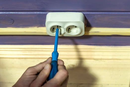 Closeup of man's hand installing socket on wooden wall at country house photo