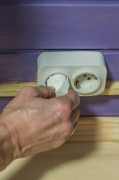 hand unplugging a plug from a socket photo