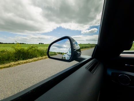 View into the side mirror of a black sports car while driving. photo