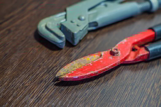 scissors for cutting metal and gas wrench on wooden table photo