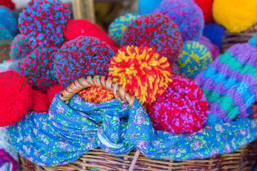 A woven basket full of bright knitted caps with large pompoms photo