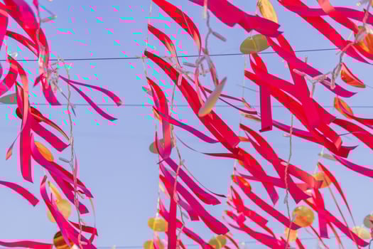 red strips of cloth hanging on a string against blue sky photo
