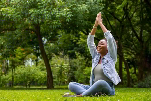 African American woman relaxingly practicing meditation yoga and stretching in the forest to attain happiness from inner peace wisdom for healthy mind and soul concept photo
