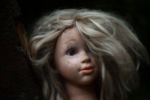 Doll's head is in mud. Children's toy. Dirty rubber girl's head with hair. photo