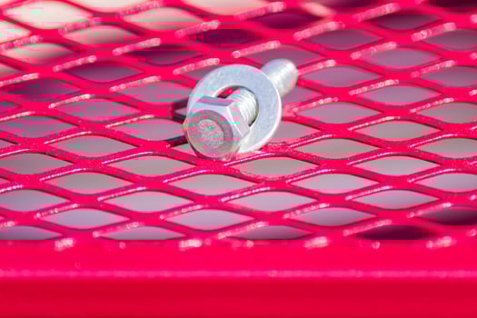 screw and nut lying on red metal grill, closeup photo