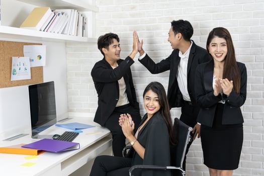 Happy business team applauding. Business people working together on project and brainstorming in office. Friendly diverse employees congratulating businesswoman with business achievement. photo