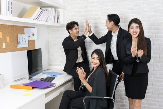Happy business team applauding. Business people working together on project and brainstorming in office. Friendly diverse employees congratulating businesswoman with business achievement. photo