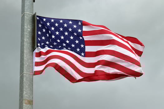 USA flag at a flagpole moving slowly in the wind against the sky photo