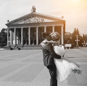 groom holds bride in his arms and twisted photo