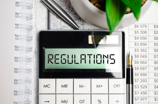 regulations word on calculator display and pen, charts on wooden background photo
