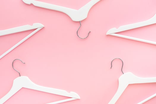 White hangers on pastel pink background photo