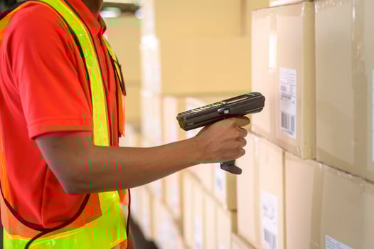 Young worker wearing helmet scanning parcels for retail and transport shipping in modern warehouse. photo
