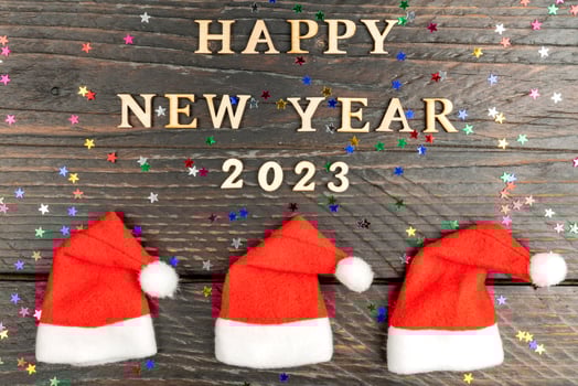 festive greeting card for 2023 new year with red santa hats in a row and wooden text on a table. photo