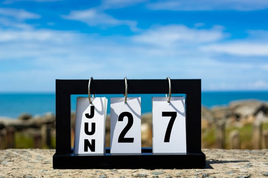 Jun 27 calendar date text on wooden frame with blurred background of ocean. photo