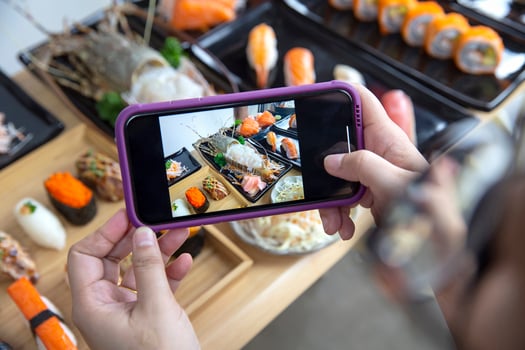 Woman photographing food served Japanese sushi set , Sushi nigiri rolls and sashimi in japanese food restaurant menu photo