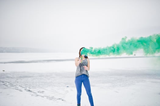 Young girl with green colored smoke bomb in hand in winter day. photo