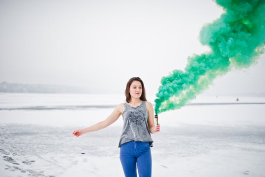 Young girl with green colored smoke bomb in hand in winter day. photo