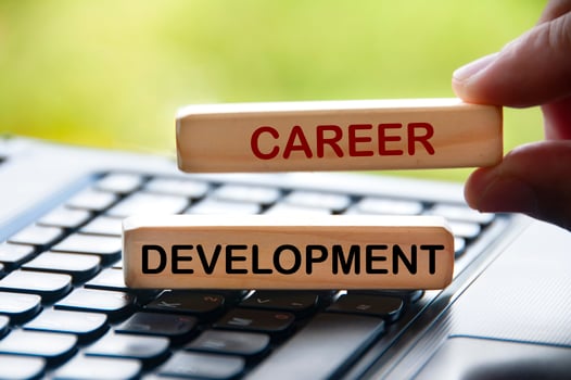 Hand holding wooden blocks with text on laptop keyboard - Career development. photo
