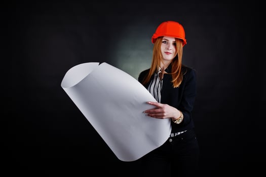 Engineer woman in orange protect helmet with construction paper projekt. photo
