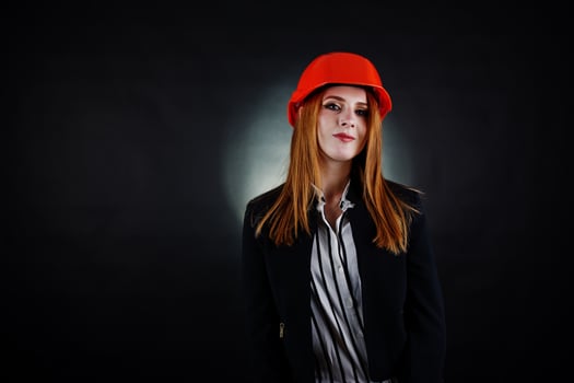 Engineer woman in orange protect helmet on studio black background. photo