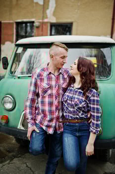 Stylish couple wear on checkered shirt in love together against old minivan. photo