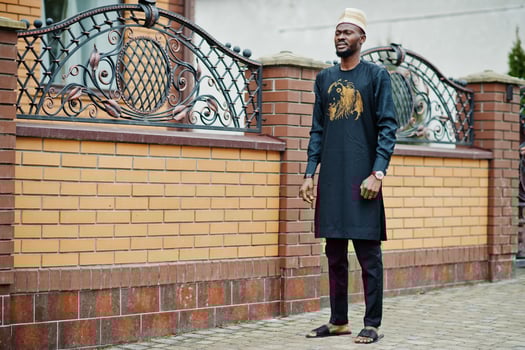 Rich african man in stylish traditional clothes and hat posed outdoor background his mansion. photo