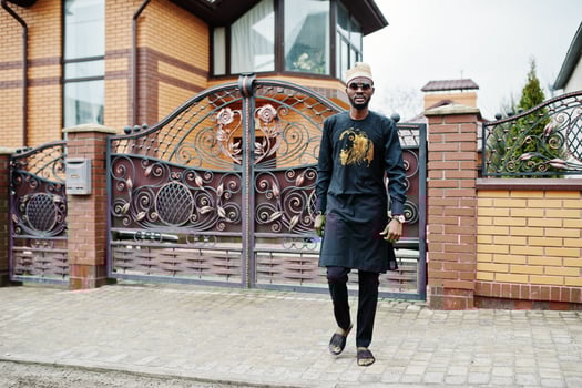 Rich african man in stylish traditional clothes and hat posed outdoor background his mansion. photo