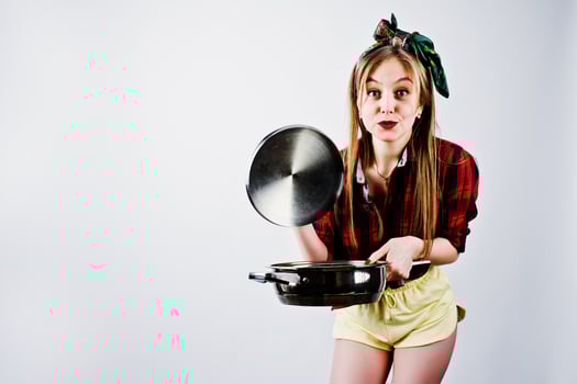 Young funny housewife in checkered shirt and yellow shorts pin up style with frying pan isolated on white background. photo