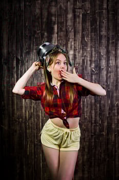 Young funny housewife in checkered shirt and yellow shorts pin up style with kitchen sieve on wooden background. photo