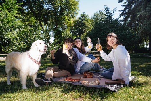 Company of beautiful young people and dog having an outdoor lunch. photo