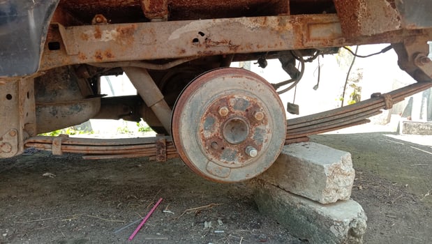 The car tire wheel rim is rusty, it's stuck with a rock photo