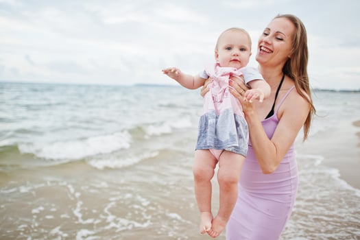 Summer vacations. Parents and people outdoor activity with children. Happy family holidays. Pregnant mother with baby daughter on sea sand beach. photo