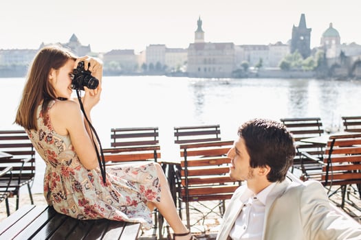 Handsome male poses at camera, being in good mood, spends free time with girlfriend who photographs him, wonderful landscape in background. Female and male active tourists go sightseeing together photo
