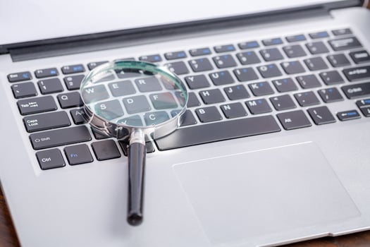 Laptop computer keyboard with magnifying glass, concept of search photo