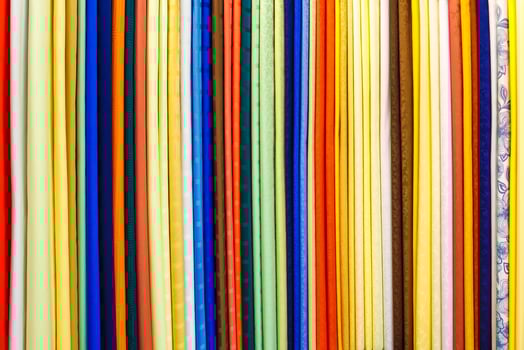 wide selection of different color textile silk fabrics clothes lay in row in drapery store photo