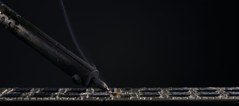 Repair of the chip. An old soldering iron is soldering a microchip in close-up. photo