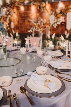 Flower arrangement for summer wedding, made of roses and green branches on a dinner table in the restaurant. , glass and plates in the restaurant outside on a windy day with film grain effect photo