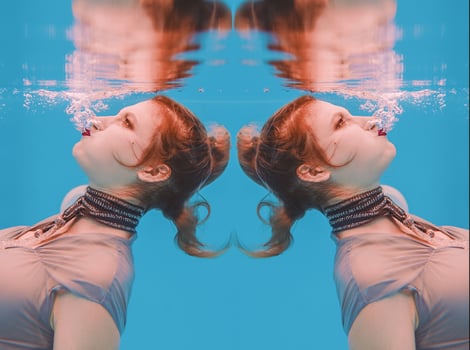 surreal art portrait of young woman in grey dress and beaded scarf underwater in the swimming pool photo
