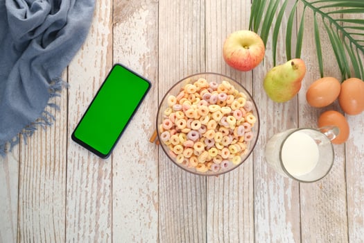 top view of colorful cereal corn flakes in a bowl and smart phone on table photo